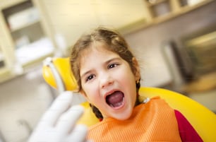 Menina está tendo seus dentes verificados pelo dentista