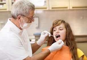 Teenager-Mädchen mit der Zahnspange an den Zähnen wird beim Zahnarzt behandelt