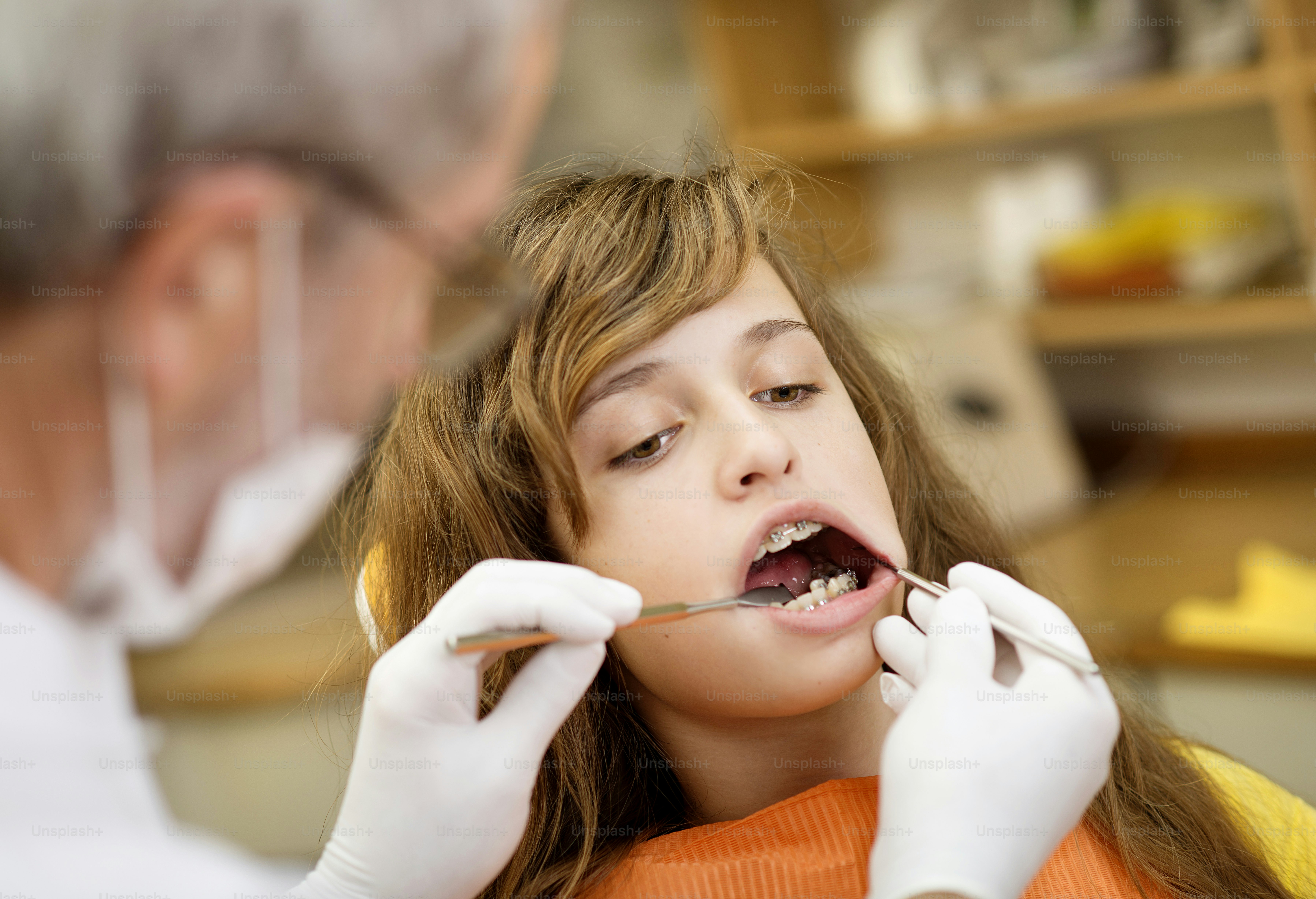 Teenage girl with the braces on her teeth is having a treatment at dentist