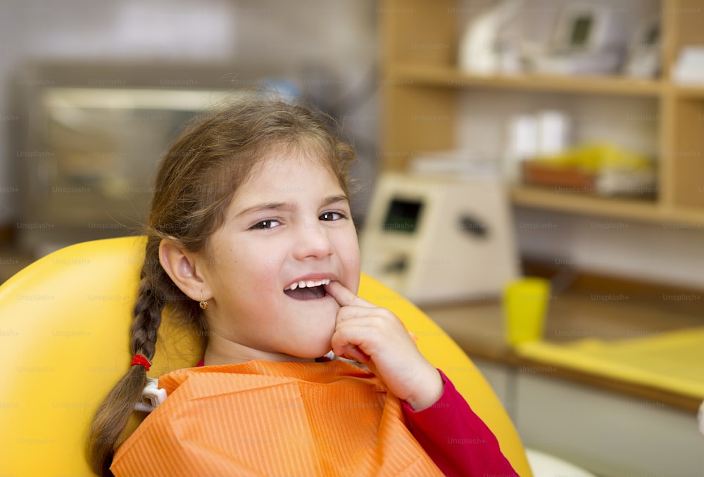 어린 소녀는 치과에��서 치아를 검사하고 있습니다.
