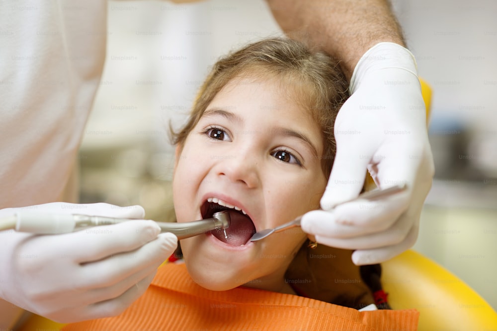 Little girl is having her teeth examined by dental specialist