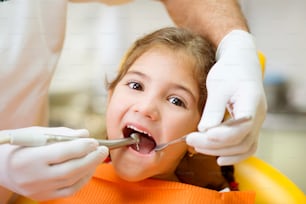 Une petite fille se fait examiner les dents par un dentiste