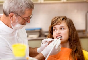 Une adolescente avec les broches sur les dents suit un traitement chez le dentiste