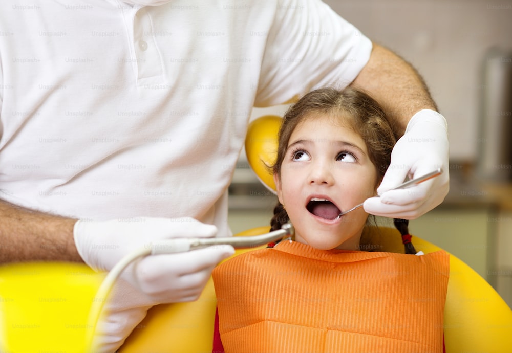 Little girl is having her teeth checked by dentist
