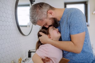 バスルームで幼い娘にキスをする父親。