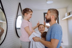 Un padre con tres niños pequeños en el baño, concepto de rutina matutina.