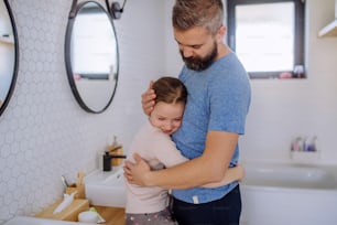 Um pai feliz abraçando sua filhinha no banheiro.