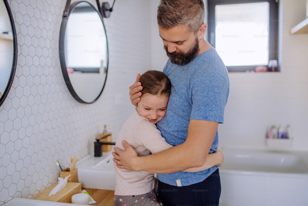 Ein glücklicher Vater, der seine kleine Tochter im Badezimmer umarmt.