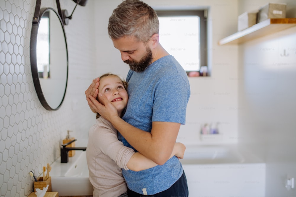 Um pai feliz abraçando sua filhinha no banheiro.