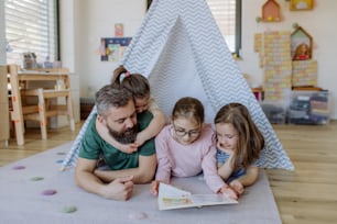 집에서 책을 읽어주는 세 딸의 쾌활한 아버지.