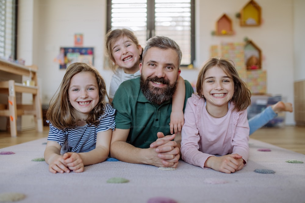 Um pai alegre com três filhas pequenas brincando juntas em casa.