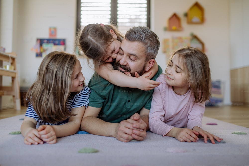 A cheerful father with three little daughters playing together at home.