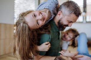 Un padre allegro con tre figlie piccole che giocano insieme a casa.