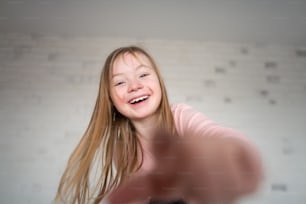 A happy little girl with Down syndrome looking at camera at home.