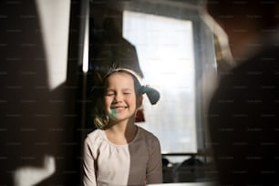Ein kleines Mädchen mit blauem Fleck im Gesicht, das zu Hause mit geschlossenen Augen lächelt.