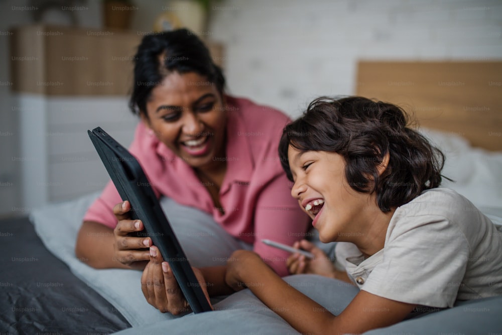 An Indian mother using tablet with her little son and having fun at home.