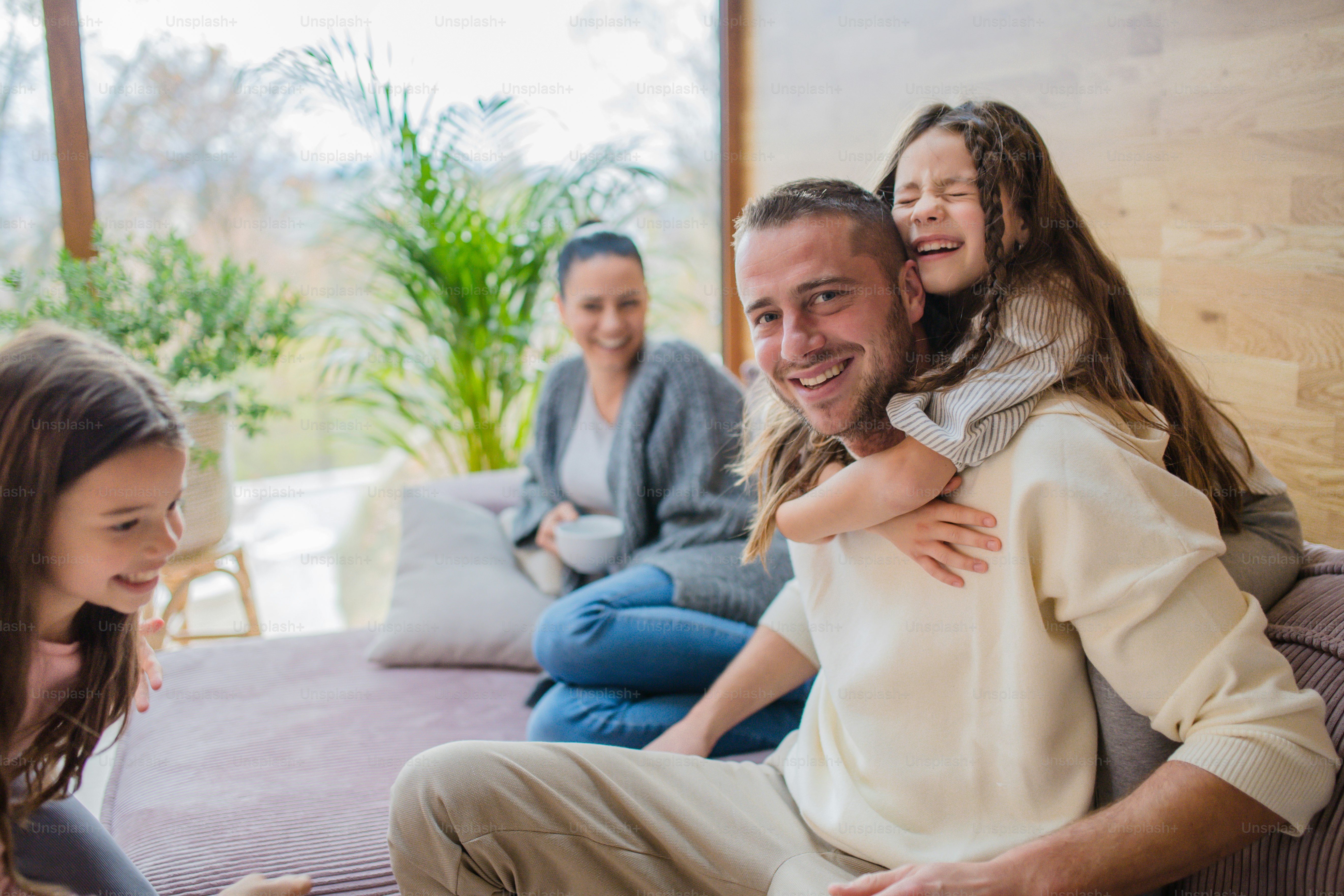 Two happy sisters having fun with a father at home