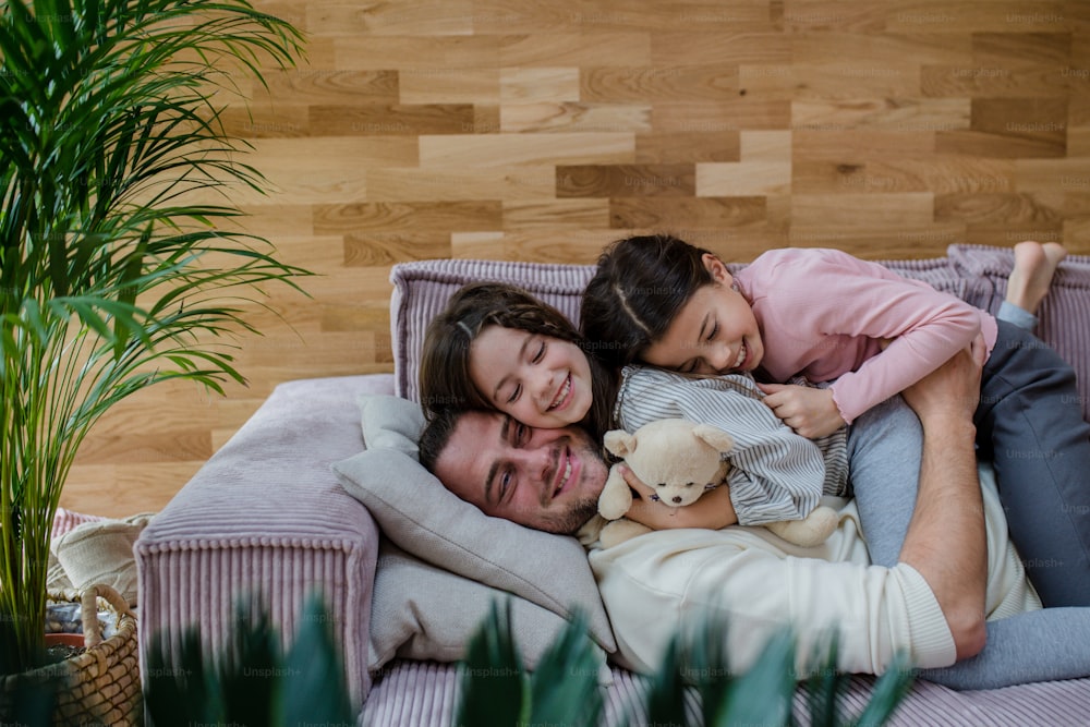 행복한 두 자매가 아버지와 즐거운 시간을 보내고, 집에서 소파에 누워 있다.
