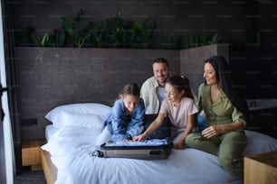 A happy young family with two children enetring room at luxury hotel, summer holiday.