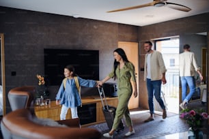 Une jeune famille heureuse avec deux enfants enetling chambre à l’hôtel de luxe, vacances d’été.