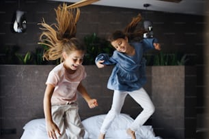 Deux petites sœurs sautant sur un lit à l’intérieur de l’hôtel.