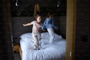Zwei kleine Schwestern, die drinnen im Hotel auf ein Bett springen.