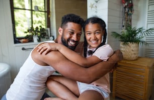 Porträt eines glücklichen jungen Mannes mit kleiner Schwester drinnen zu Hause, umarmend.