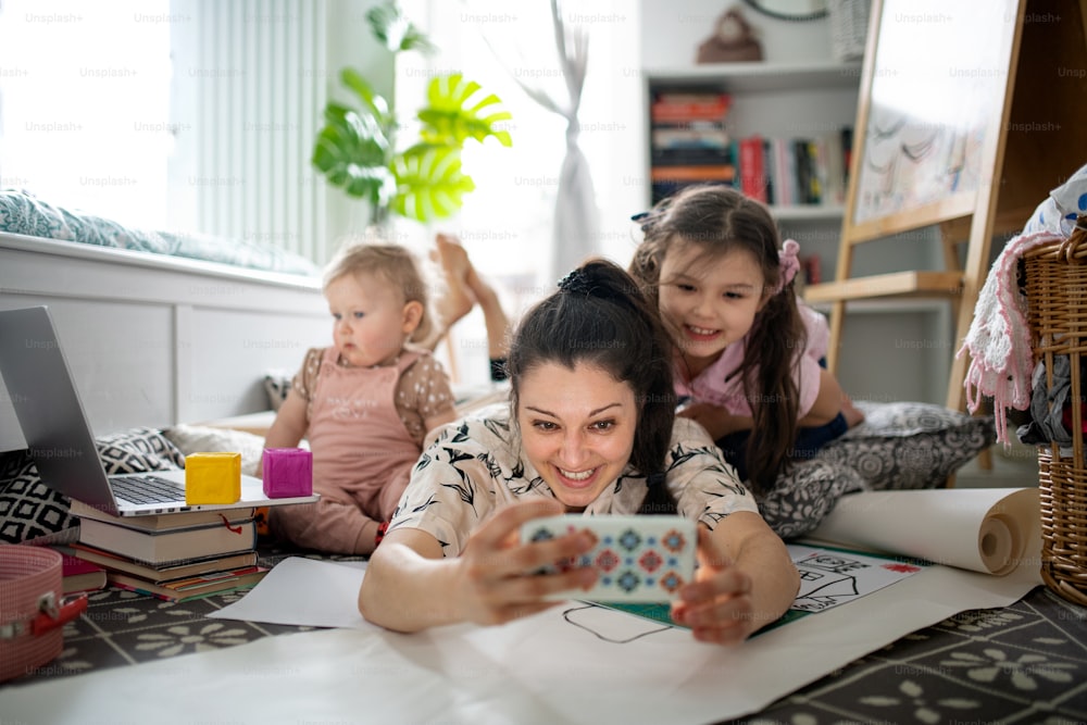 Mother working with two small daughters in bedroom, home office concept.