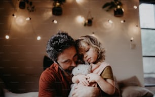 Ein reifer Vater mit trauriger kleiner Tochter, die sich zu Hause umarmt.