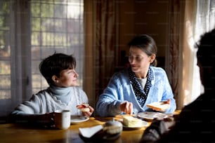 Un portrait de petite fille heureuse et triste avec des parents mangeant à l’intérieur à la maison, concept de pauvreté.