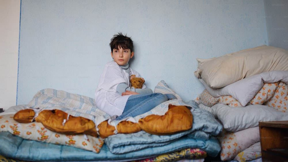 Povera bambina triste seduta sul letto in casa a casa, concetto di povertà.