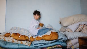 불쌍한 슬픈 어린 소녀는 집에서 침대에 앉아 있고, 빈곤 개념이다.