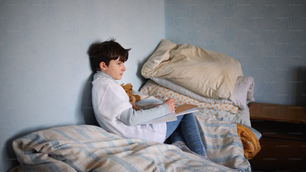 Povera bambina triste seduta sul letto in casa a casa, concetto di povertà.