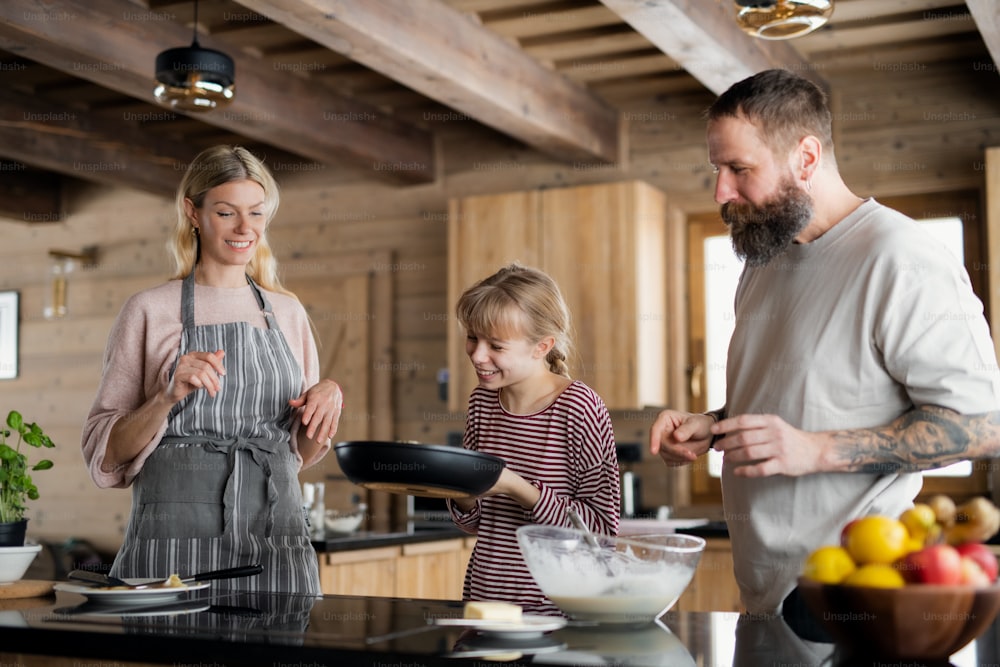 小さな娘が屋内で料理をする幸せな家族、民間アパートでの冬の休日。