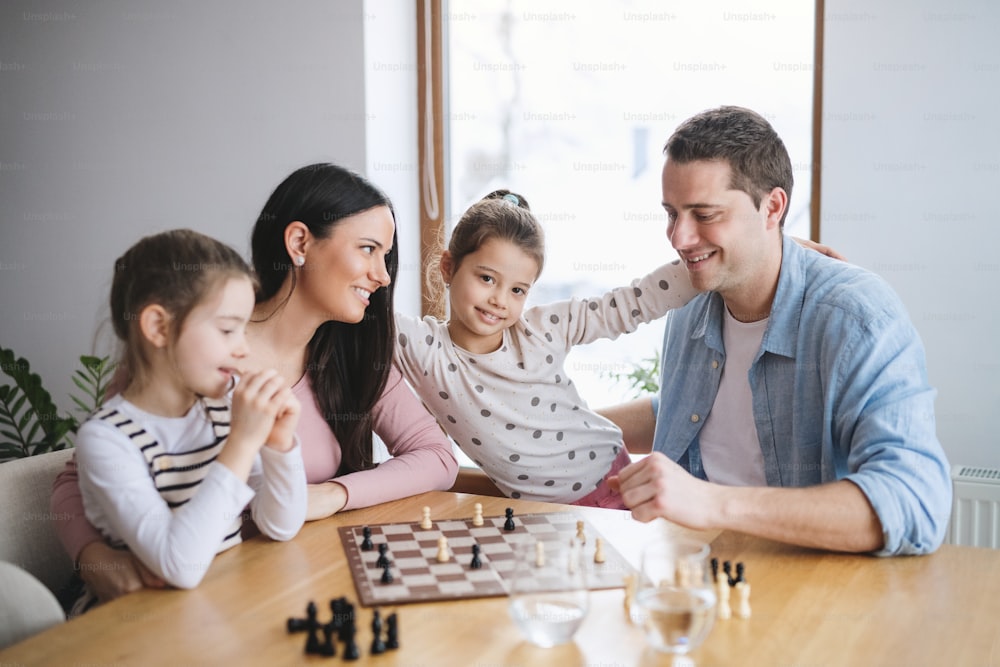 Parents with happy small girls indoors at home, playing board games.