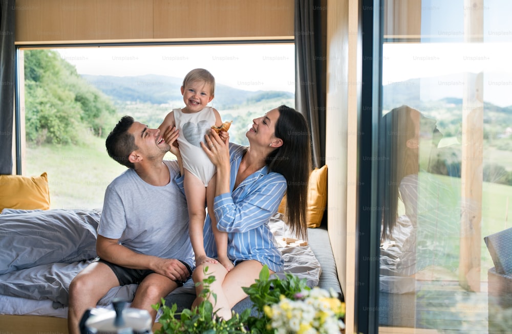 Happy young woman with husband and baby indoors, weekend away in container house in countryside.