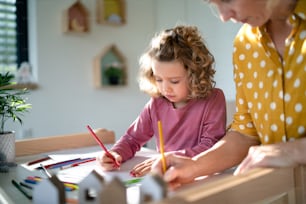 Una bambina carina con la madre in camera da letto in casa a casa, disegnando immagini.