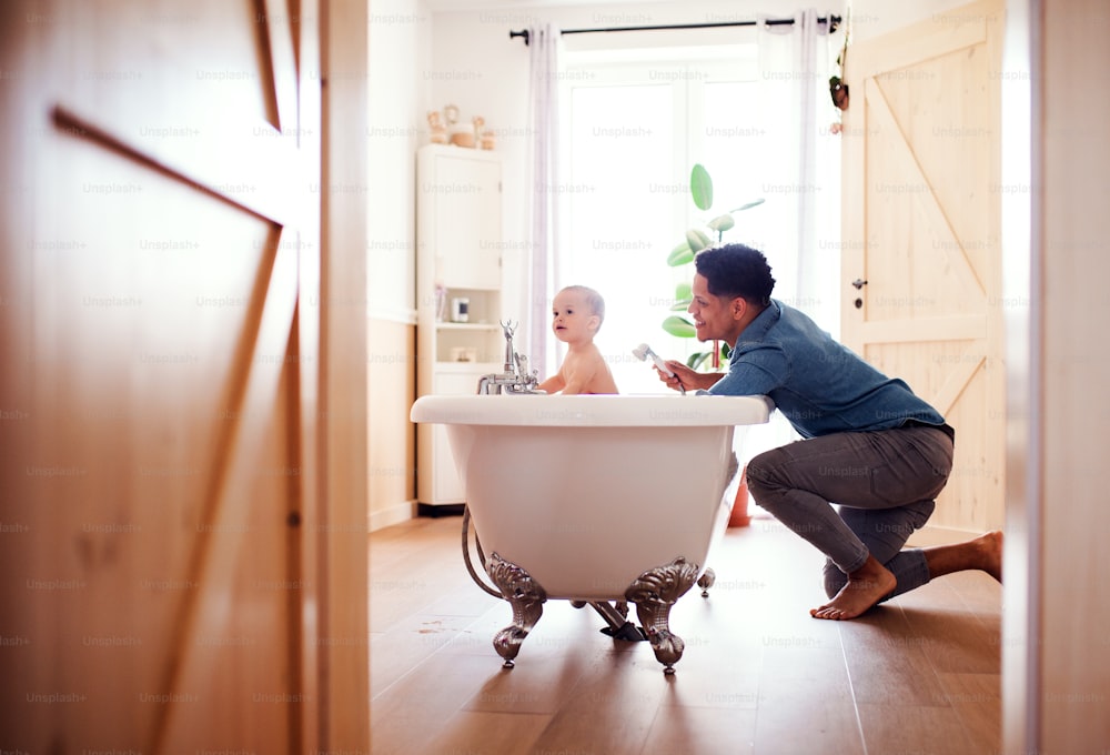 Padre hispano lavando a su hijo pequeño en un baño en el interior de su casa.