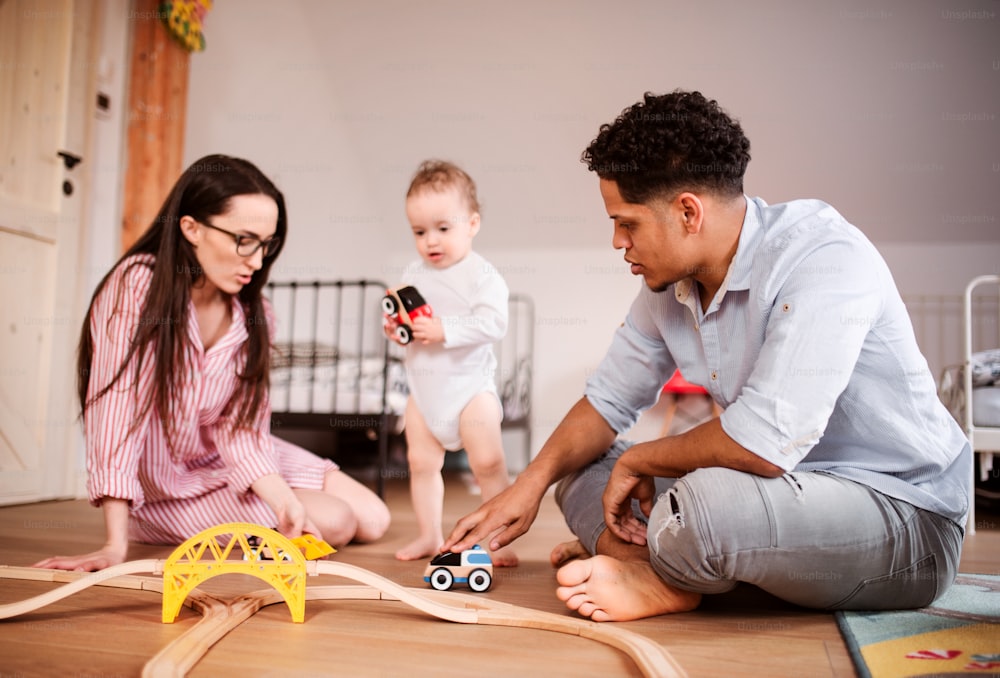 A young family with small toddler son indoors at home, playing.