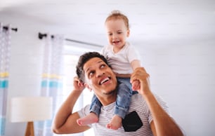 Cheeful father and small toddler son indoors at home, playing.