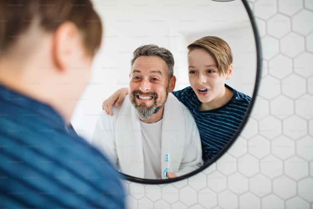 Ein reifer Vater mit kleinem Sohn morgens im Badezimmer beim Zähneputzen.