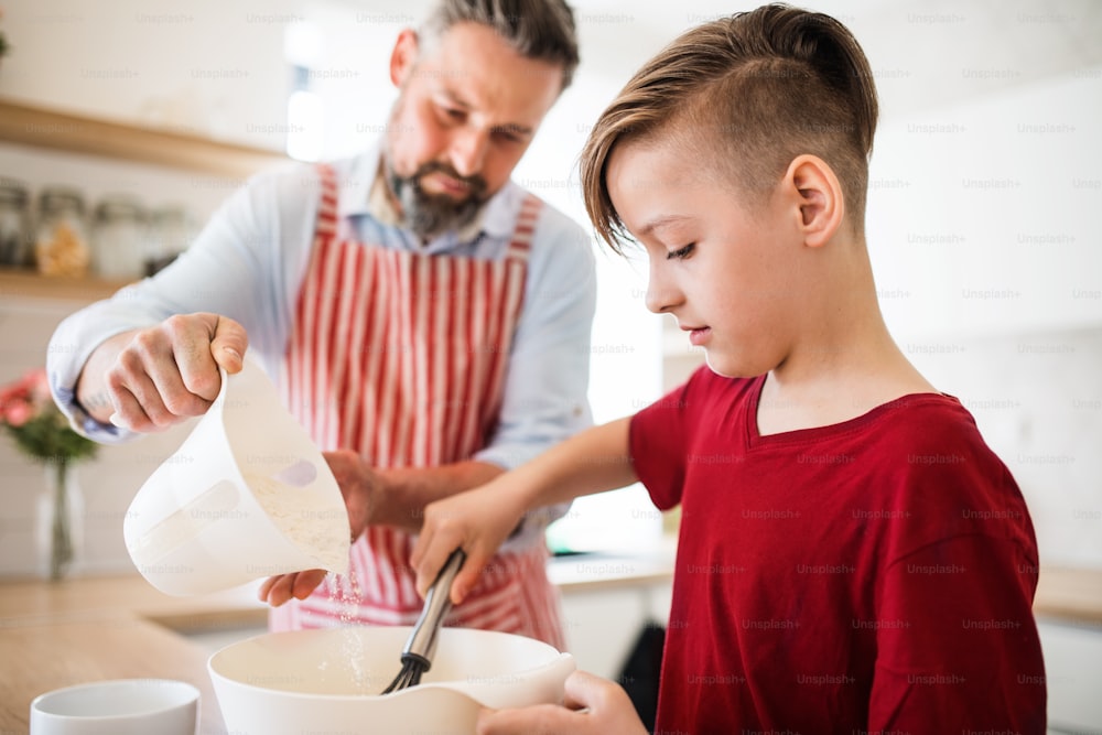 キッチンの屋内で小さな息子を持つ成熟した父親で、パンケーキを作る。