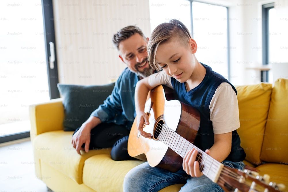 어린 아들을 둔 성숙한 아버지는 실내 소파에 앉아 기타를 연주한다.