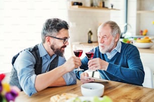 大人の流行に敏感な息子と年配の父親が自宅の屋内のテーブルに座って、軽い昼食を食べています。