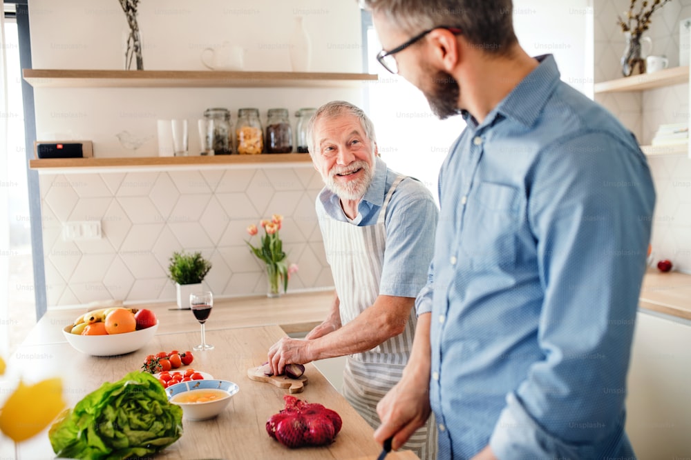 大人の流行に敏感な息子と年配の父親が自宅のキッチンで屋内で料理をしている。