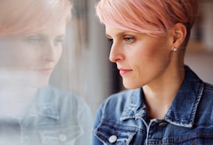 A close-up portrait of young attractive woman standing by window at home. Copy space.