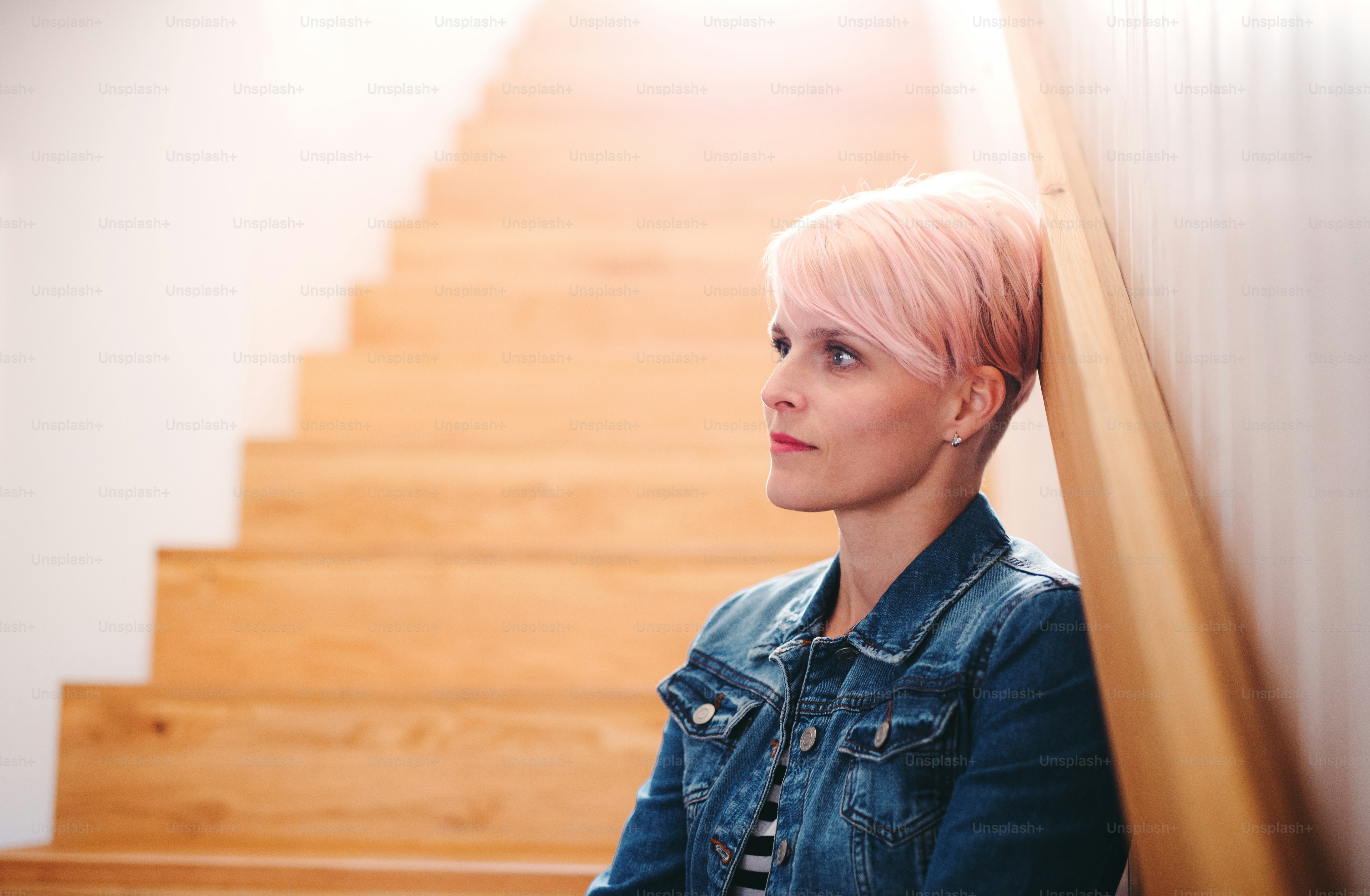 A young attractive woman sitting at the bottom of the stairs at home. Copy space.