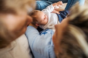 Uma vista superior de jovens pais irreconhecíveis com um bebê recém-nascido em casa.