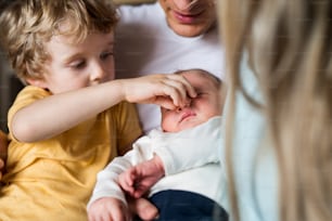Young parents with a newborn baby and small toddler son at home, a close-up.