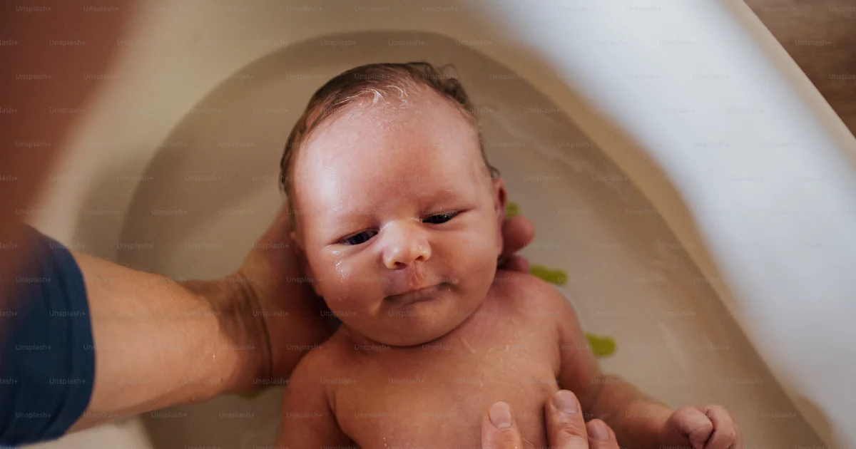 Bañando Vista superior de un padre irreconocible bañando a un bebé recién ...